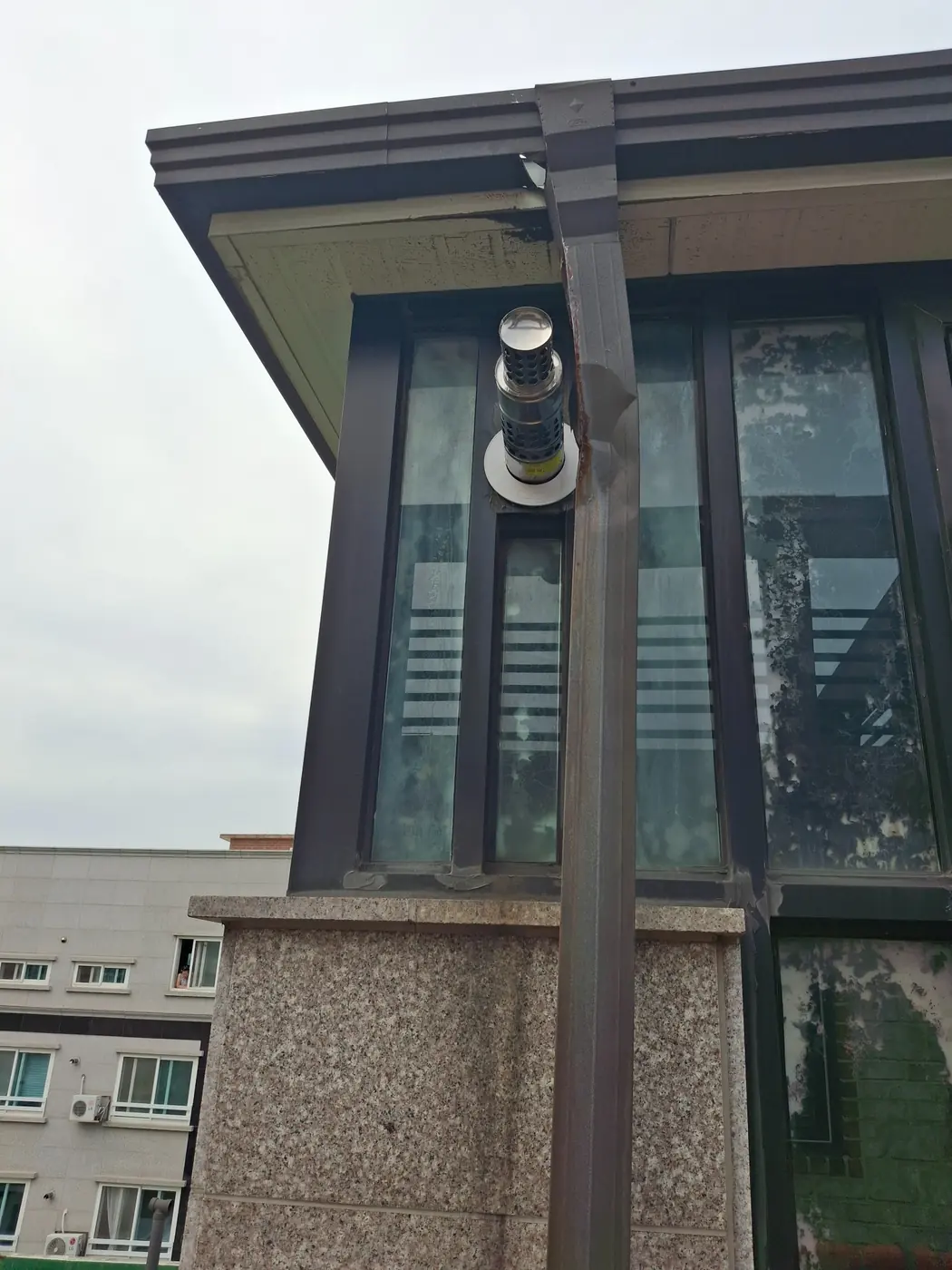 시공 후 절곡 금속 연결 부재로 상부 빗물받이와 하부 선홈통을 연결한 상태