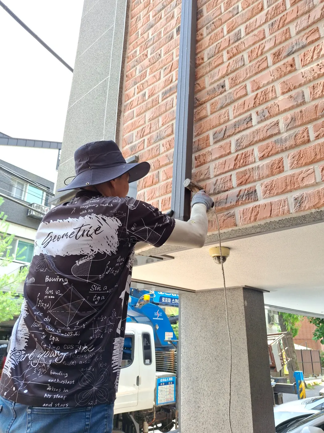 빌라 외벽에 사각 금속 우수관을 세우고 고정하는 작업